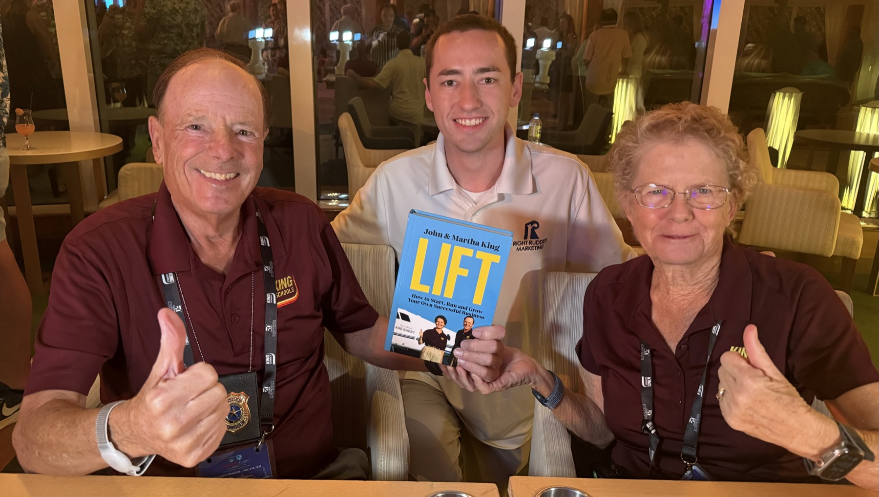 Sam with John and Martha King of King Schools, holding their business book LIFT